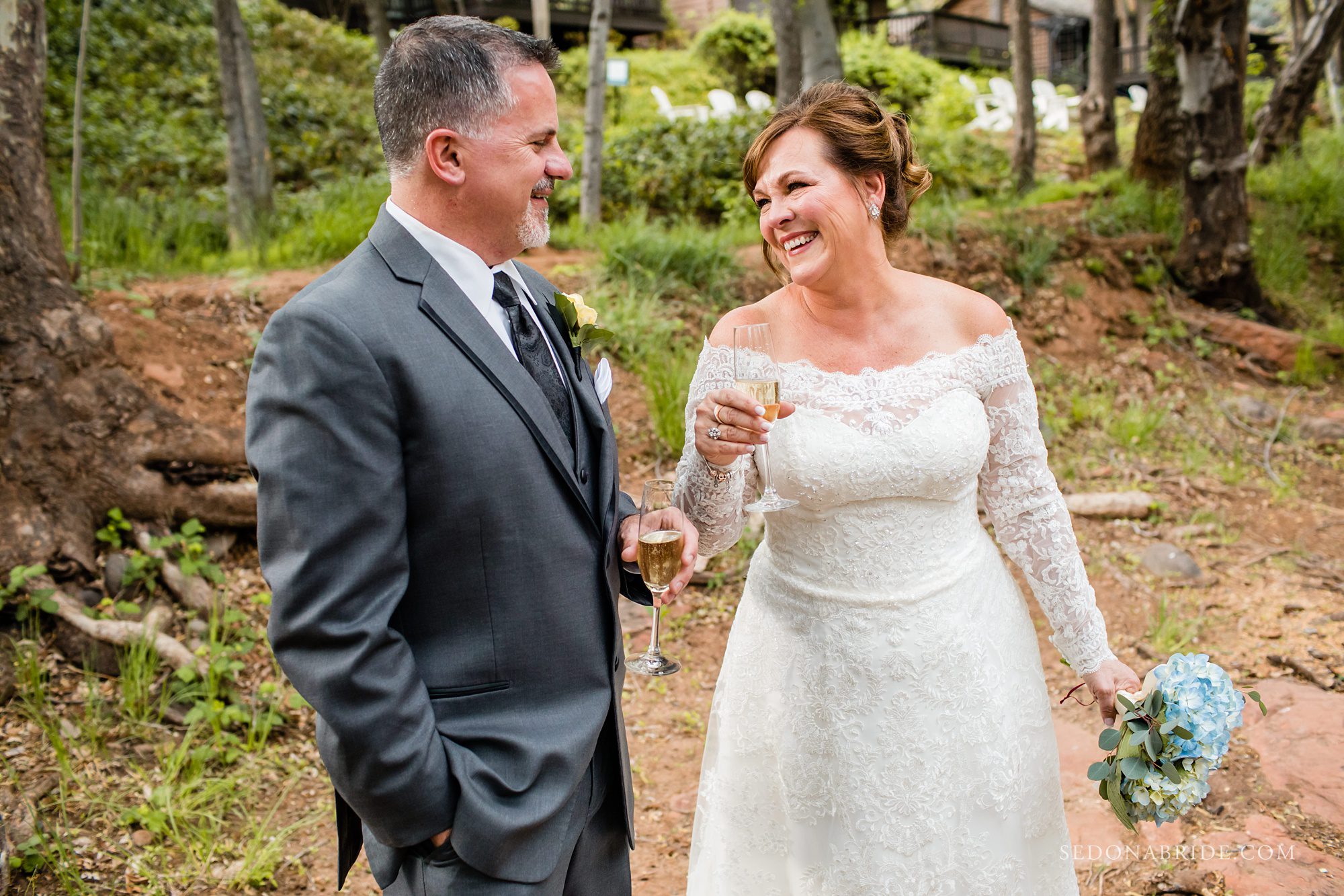 Groom in a grey suit and bride in off the white wedding dress laughing together