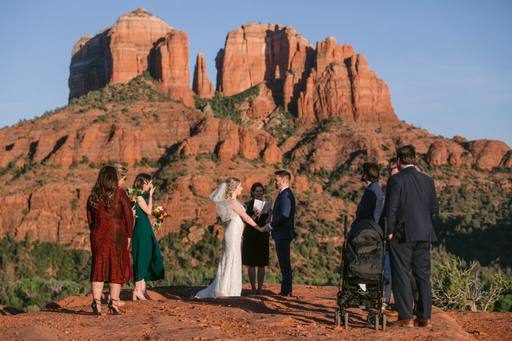 Maid of honor dressed in green, cries, while the bride and groom are married in front of Cathedral Rock.