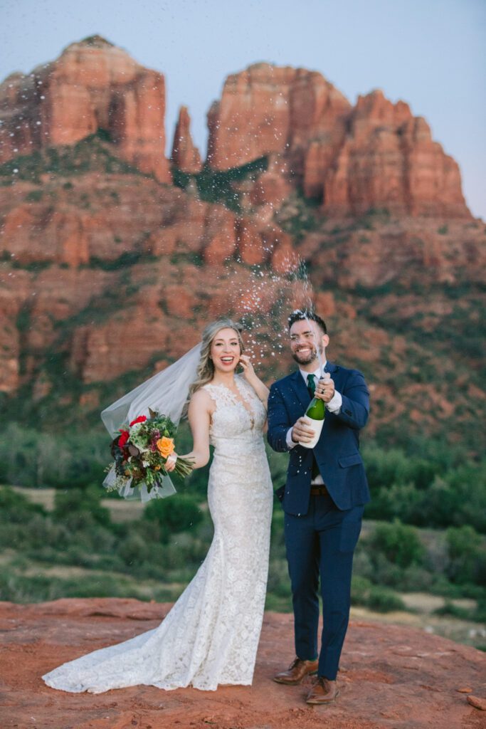 Groom pops the cork on a champagne bottle.