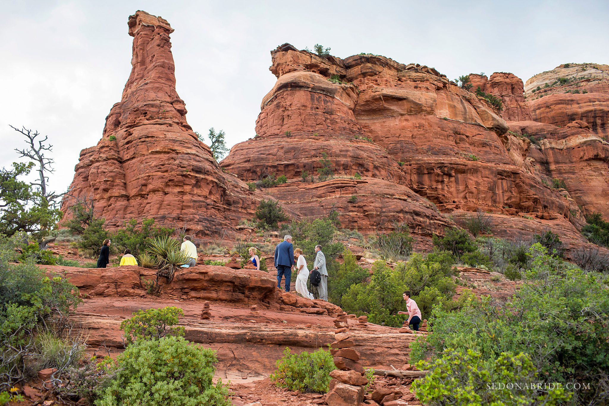 Bride and groom and guests hiking the red rocks to a ceremony location at Enchantment Resort