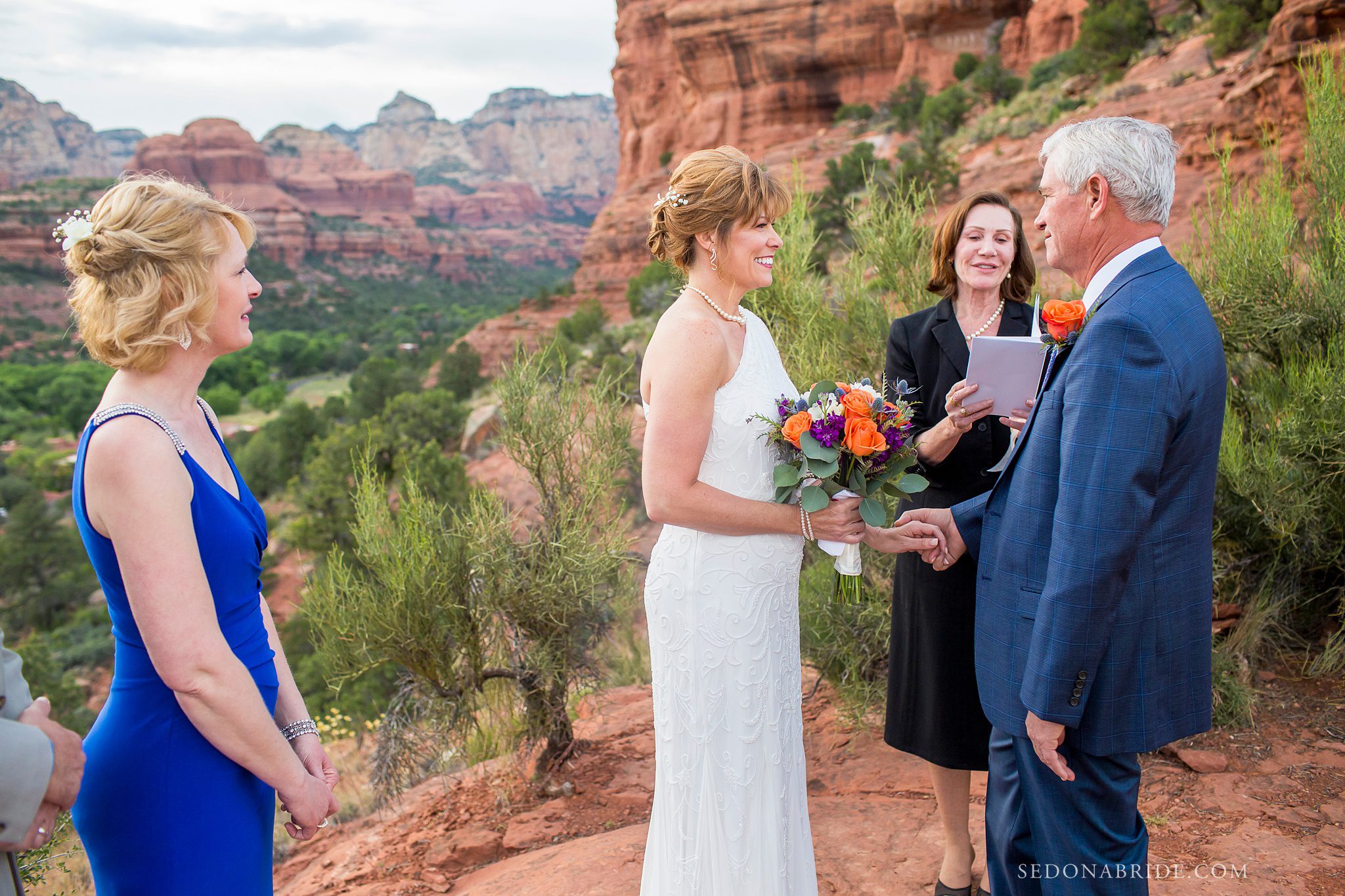 Bride and groom exchanging vows at Enchantment Resort with red rocks in the background