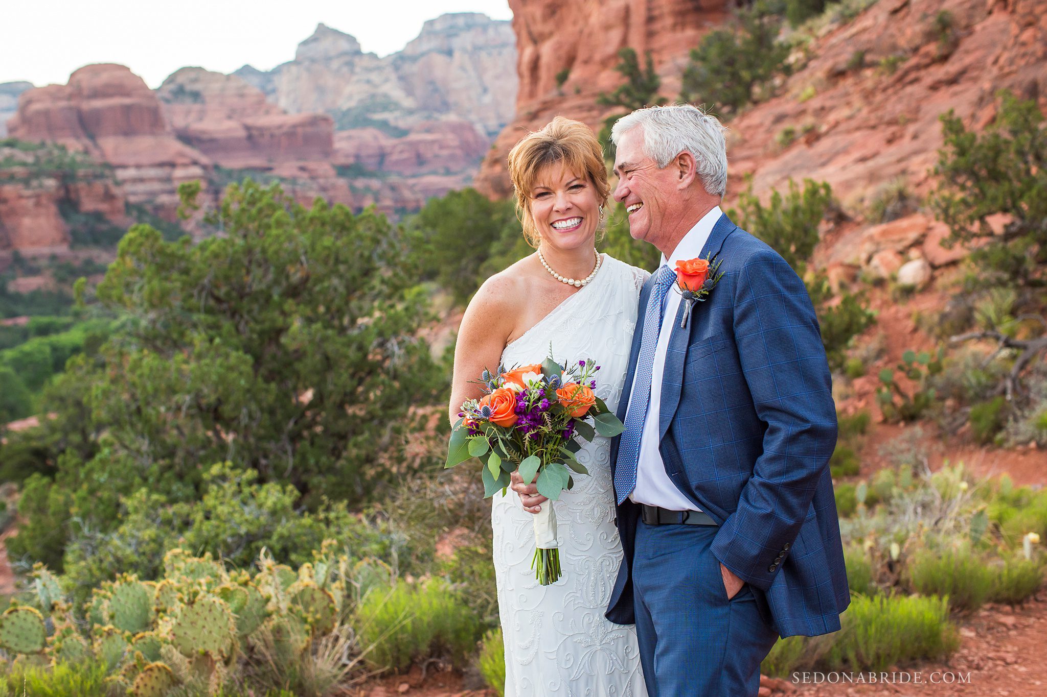 newly married couple smiling with the red rocks of Enchantment Resort behind them
