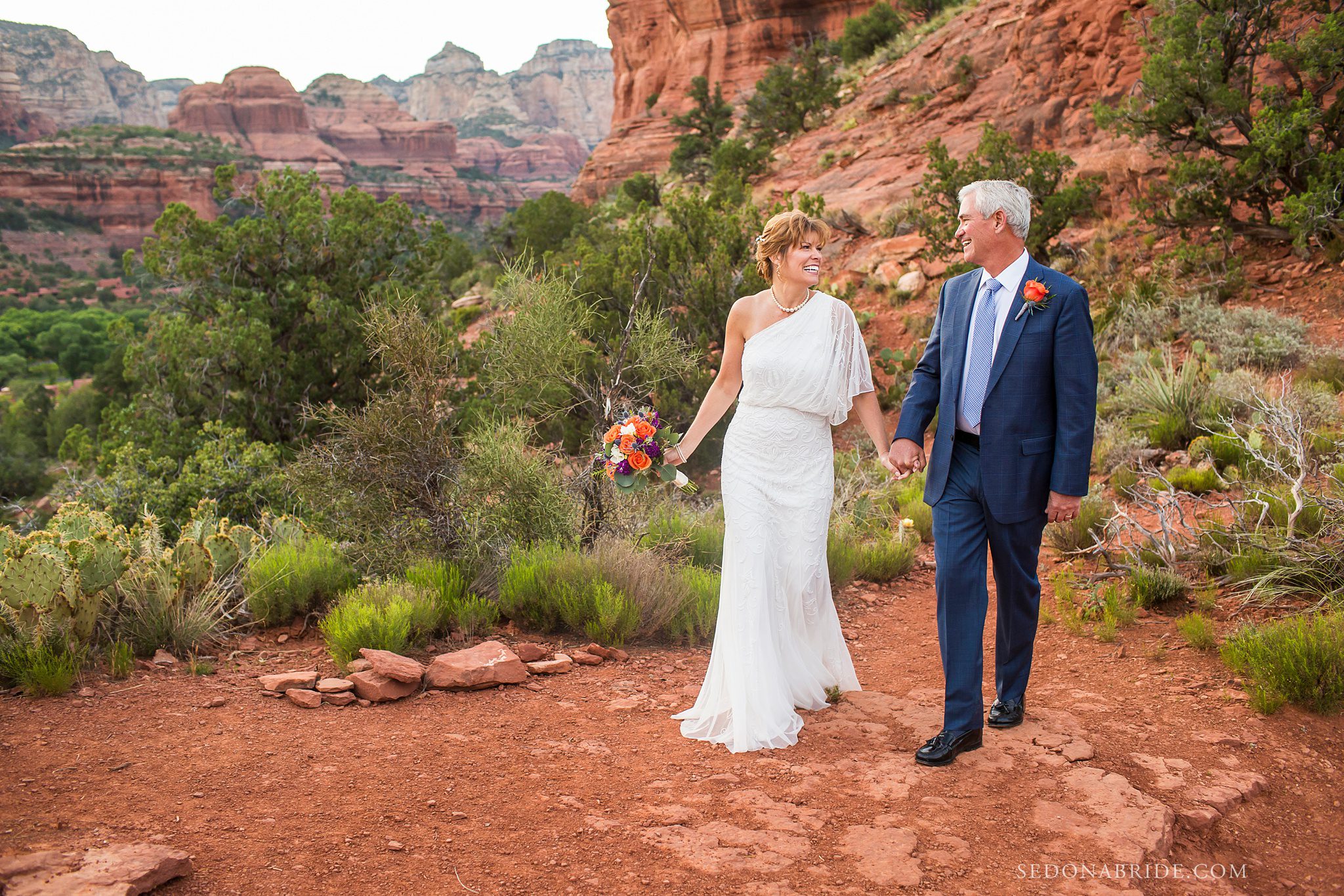 Bride and groom walking with the red rock backdrop behind them