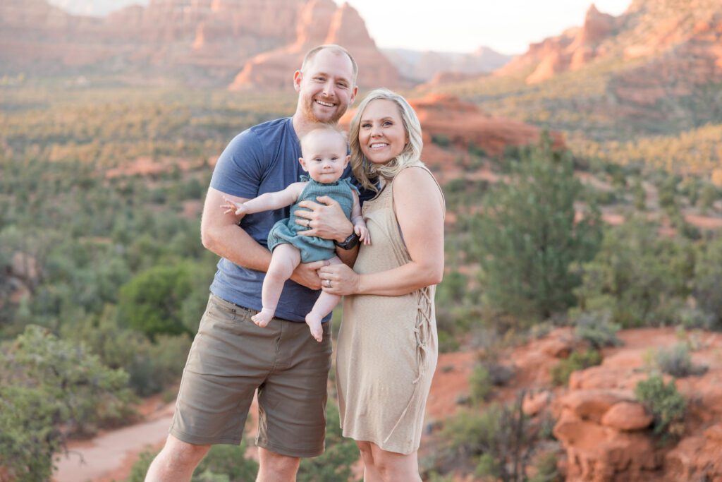 A young family poses fo a family photo in Sedona at sunset.